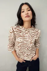 Blusa color beige con estampado abstracto en blanco, corte relajado, mangas 3/4 fruncidas y cuello con volados.