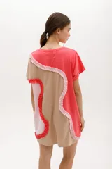 Vestido corto de algodón, con bloques de color en tonos pastel (amarillo claro, beige y rosado pálido) unidos por volados fruncidos en tonos marrón claro y amarillo. Presenta cuello redondo y mangas cortas.