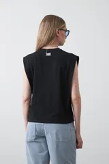 Remera sin mangas negra con hombros marcados y caída recta.