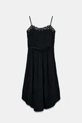 Vestido midi negro de escote recto y tirantes finos. Presenta detalles de encaje combinado a tono en el escote y en la cintura, con bajo asimétrico.