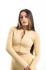 Top deportivo color amarillo claro, de tejido acanalado y corte ajustado, con cierre frontal y logo bordado en el pecho.