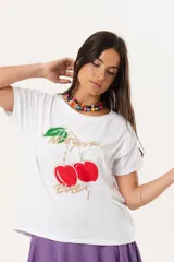 Remera blanca de algodón y elastano, con cuello redondo y mangas cortas. Estampado frontal con cerezas y texto en dorado.