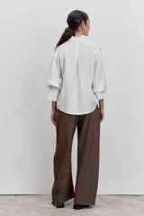 Camisa azul de manga larga con cuello alto fruncido y puños elásticos.