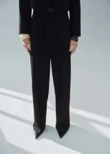 Pantalon de vestir negro de corte recto y tiro medio, con trabillas en la cintura, cierre oculto y lazo ajustable. Cuenta con bolsillos laterales y forro interior.