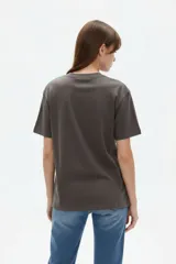 Remera de algodón manga corta, corte holgado, con cuello redondo y estampado frontal en negro con la frase "Travel through the universe" y motivos celestes de sol, luna y estrellas.