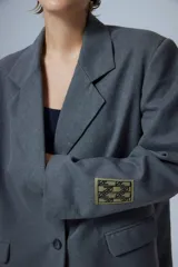 Saco sastrero oversize gris con bolsillos delanteros, forro de tafeta a tono, bordado en la tapa del bolsillo y etiqueta RENÉE tejida.