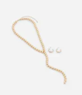 Conjunto de collar tipo lazo y aros tipo argolla, confeccionados en metal dorado con detalles de esferas.