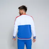 Buzo de cuello redondo Umbro del Club Nacional de Football. Diseño tricolor con cuerpo superior blanco, franja central azul y detalles en rojo en hombros y puños. Incluye logo de Umbro y escudo del club en el pecho.