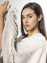 Ruana de punto color beige con sutiles motas multicolores, con bordes terminados en flecos largos.