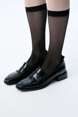 Mocasín de cuero charol negro con punta cuadrada, detalle de tiento y tirador trasero.