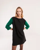Vestido corto negro con mangas 3/4 verdes, cuello bote y bolsillos laterales.