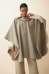 Poncho de lana fina sin teñir, con cuello camisero, cartera con broches a presión y bolsillo ojal. Diseño de estilo campestre con textura tejida.