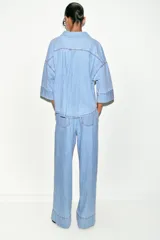 Jeans de tiro medio con corte wide leg y pinzas delanteras. Presenta bolsillos frontales, bolsillos de plastrón en la parte trasera, cierre frontal con cremallera, botón interior y ganchos metálicos.