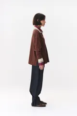 Sweater de punto color marrón con cuello polo en contraste color crema. Presenta diseño de rayas verticales texturizadas, mangas largas con puños en color crema y corte holgado.