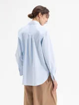 Camisa de algodón con lycra en color celeste claro, de corte clásico y manga larga. Presenta apliques de piedras de cristal en las puntas del cuello y una cartera oculta con botones.