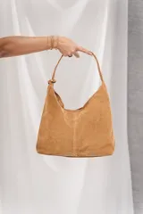 Cartera tipo hobo de cuero sintético marrón oscuro, con diseño slouchy y costura central vertical. Posee asa corta integrada al cuerpo del bolso.