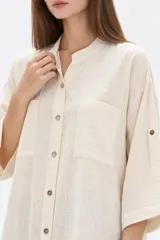 Túnica de algodón color marrón, con cuello mao, bolsillos frontales, cierre de botones y mangas largas con presilla para arremangar.