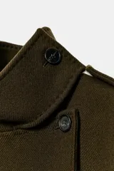Abrigo de corte recto confeccionado en mezcla de lana, color verde oscuro. Presenta cuello subido, cierre frontal cruzado con botones, mangas largas con trabillas en los hombros, bolsillos delanteros y cinturón ajustable del mismo tejido.