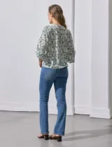 Blusa de gasa con estampado geométrico en tonos negro, gris y celeste. Tiene cuello redondo y mangas 3/4 amplias con abertura y botón.