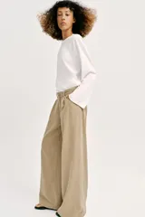 Jeans de tiro alto con pinzas delanteras, pernera ancha y fluida. Cuenta con cierre frontal de cremallera y botón, bolsillos frontales y bolsillos de plastrón en la parte trasera.