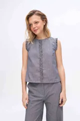 Musculosa gris a rayas verticales, con cuello redondo y detalles de volados fruncidos en la línea central delantera y en las sisas.