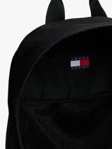 Mochila negra de diseño redondeado con acabado texturizado. Cuenta con un compartimento principal amplio, un bolsillo exterior con cremallera y un bolsillo interior de malla abierto. Tiene asas ajustables y acolchadas, asa superior y un parche tejido con el logo de Tommy Jeans en la parte delantera.