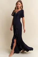 Vestido largo de fiesta color azul marino, con escote en V adornado con encaje, mangas cortas con abertura y falda con tajo lateral decorado con volados.