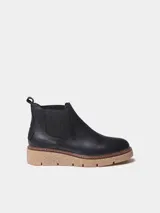Botin de mujer de cuero negro, estilo chelsea, con elásticos laterales, tirador trasero y suela dentada de goma color caramelo.
