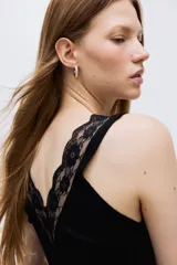 Musculosa entallada de punto acanalado, color negro, con breteles anchos y escote en V profundo decorado con ribete de encaje.