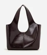 Cartera shopper grande Satinato confeccionada en PU color bordó con acabado efecto charol, diseño amplio de trapecio invertido, asas amplias para el hombro y cierre magnético.