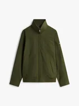 Campera Tommy Hilfiger de color verde militar, con cuello alto, cierre frontal de cremallera y bolsillos laterales. Confeccionada en poliamida, presenta un diseño clásico y versátil con el logo de la marca bordado discretamente en el pecho.
