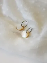 Par de aros plateados tipo argolla con dije circular de nácar.