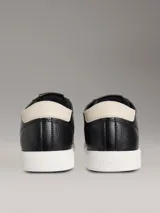 Zapatillas urbanas Calvin Klein de perfil bajo, color negro con suela blanca y detalle beige en el talón. Confeccionadas en cuero granulado, cuentan con cordones negros y el monograma de la marca grabado en el lateral.
