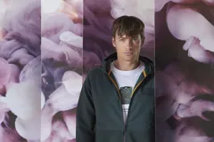 Campera verde oscuro con capucha, cierre frontal y bolsillos laterales.