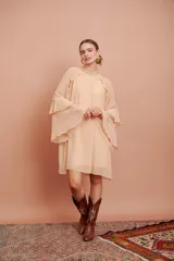 Vestido corto de manga larga acampanada con volados en cascada, color salmón claro, de corte suelto y escote redondo.