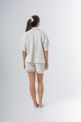 Conjunto de pijama de tela waffle color crema, compuesto por una camisa de manga corta con botones, bolsillo y detalle de broderie, y un short con elástico y cordón en la cintura con terminación de broderie.