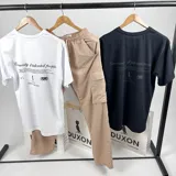 Remera oversize negra de algodón con cuello redondo y doble estampa en gris con texto y gráficos.