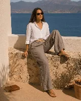Pantalón de lino color gris, de corte ancho y relajado, con cintura elástica y cinto de rafia extraíble con hebilla redonda.
