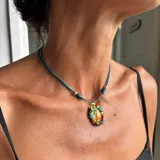 Collar ajustable con cordón azul y dije central ovalado con imagen religiosa, rodeado por una estructura de cuentas multicolores.