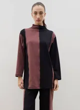 Polera de algodón con diseño bicolor en paneles verticales negros y bordó, cuello alto y tajos laterales.