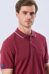 Remera polo de piqué azul marino, con cuello y puños de mangas cortas con ribete blanco en contraste, cierre frontal de dos botones y pequeño logo bordado en el pecho.