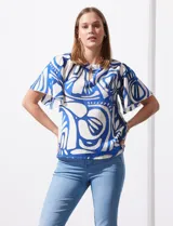 Blusa de seda fría con estampado abstracto en blanco y azul. Tiene cuello redondo con frunce, escote en V con botón y mangas cortas amplias.