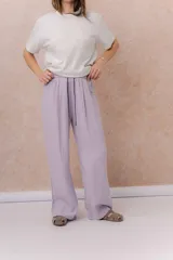 Pantalón de pierna ancha color lila, confeccionado en tela liviana con cintura elastizada y cordón de ajuste en contraste. Cuenta con bolsillos laterales.