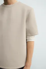 Sudadera de manga corta con corte relajado, confeccionada en tejido técnico compacto de algodón con elasticidad. Presenta cuello redondo y detalle de tacha metálica en la espalda.