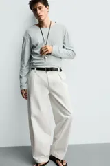 Pantalón barrel fit de hombre, confeccionado en denim de algodón color crudo. Presenta cintura con pliegues frontales, bolsillos laterales y cierre con cremallera y botón.