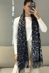 Bufanda rectangular con estampado animal print de leopardo en tonos marrones y negros, con terminación de flecos en los extremos.