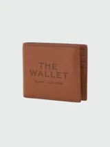 Billetera Marc Jacobs modelo The Billfold, color marrón, confeccionada en cuero con textura granulada. Cuenta con compartimentos para tarjetas y ranuras interiores, y el diseño presenta el texto "THE WALLET" y "MARC JACOBS" estampado en relieve en la parte frontal.