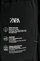 Chaqueta acolchada de color negro, resistente al agua y al viento, con aislamiento térmico. Presenta cuello subido con capucha, cierre frontal con cremallera termosellada de doble cursor, bolsillos laterales con forro polar y puños interiores elásticos.