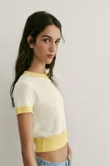 Top de punto color crudo con cuello redondo, manga corta y detalles de rib en color amarillo en el cuello, los puños y el ruedo.