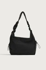 Bolso de hombro negro de nylon, con compartimento principal y bolsillos con cierre de cremallera, bolsillos laterales con cordón ajustable y asa fruncida.